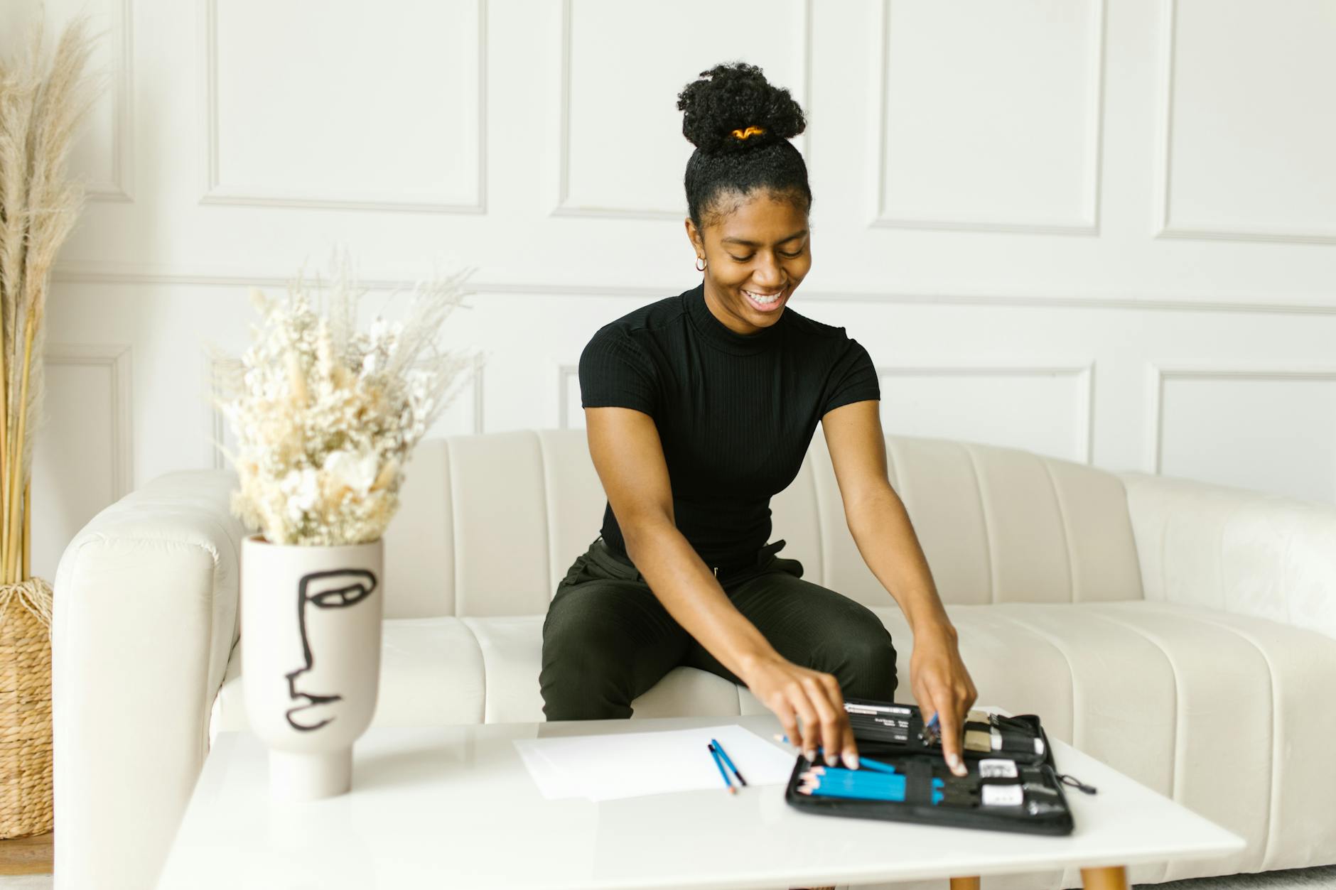 woman sitting on a sofa putting pencils on a case