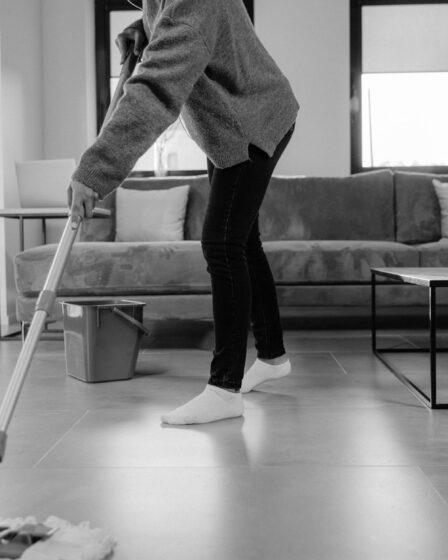 a grayscale photo of a person mopping the floor
