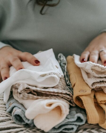 unrecognizable woman with folded clean baby clothes