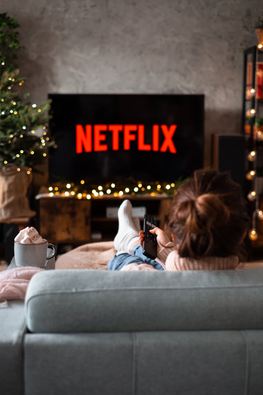 back view of a woman sitting on a sofa and watching television