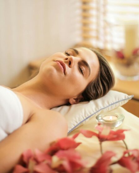 woman in wrapped in white towel lying on bed with eyes closed