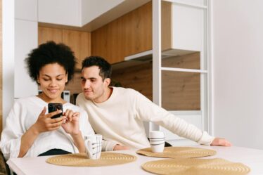 man and woman sitting at table and looking at the phone