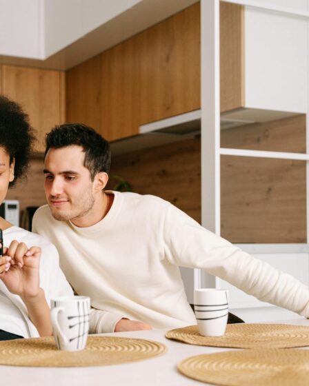 man and woman sitting at table and looking at the phone