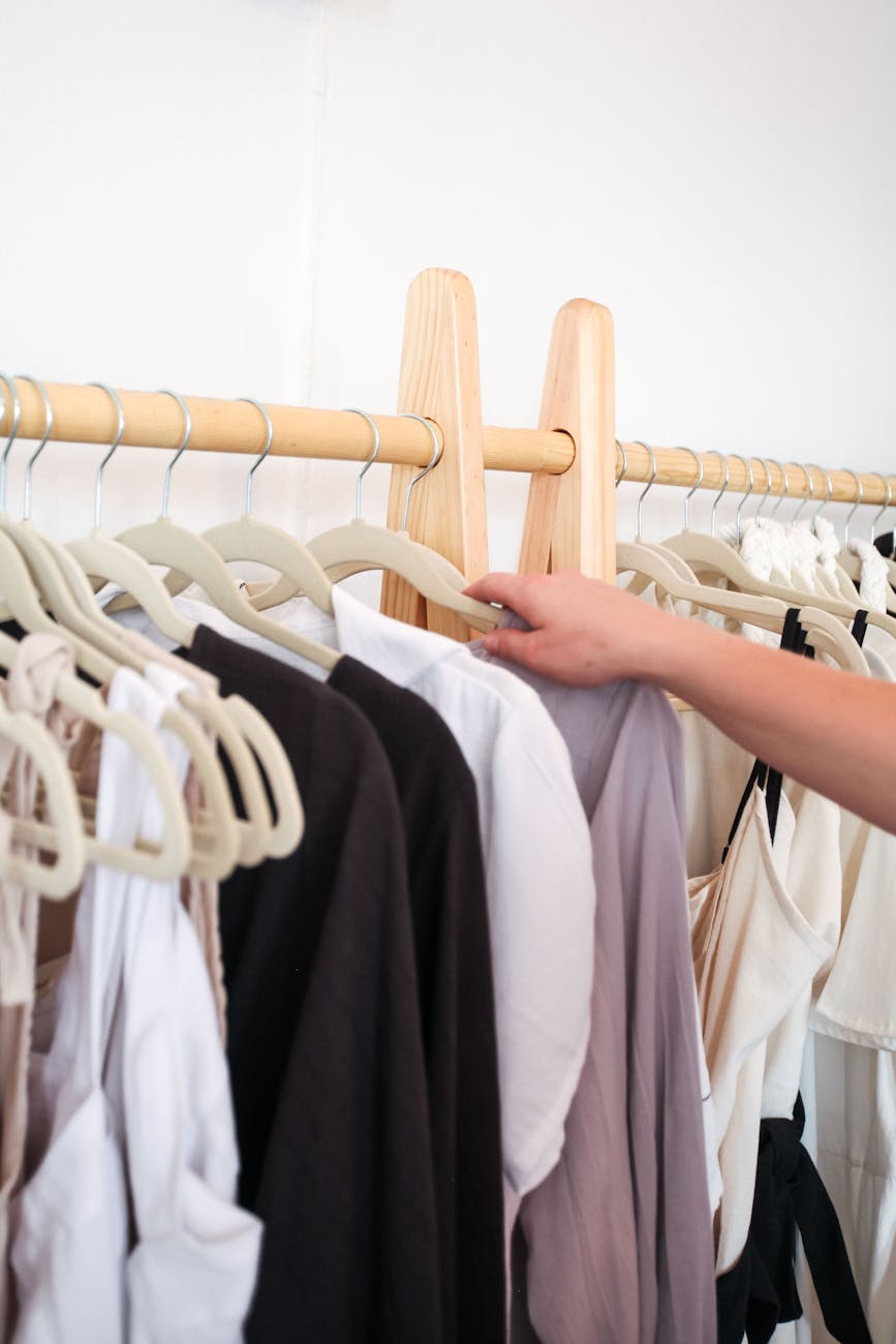 close up of person taking an item of clothing from a clothing rack