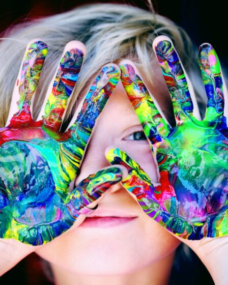 a kid with multicolored hand paint