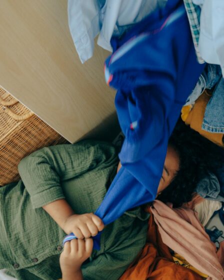 anonymous black girl lying on stack of clothes in bedroom