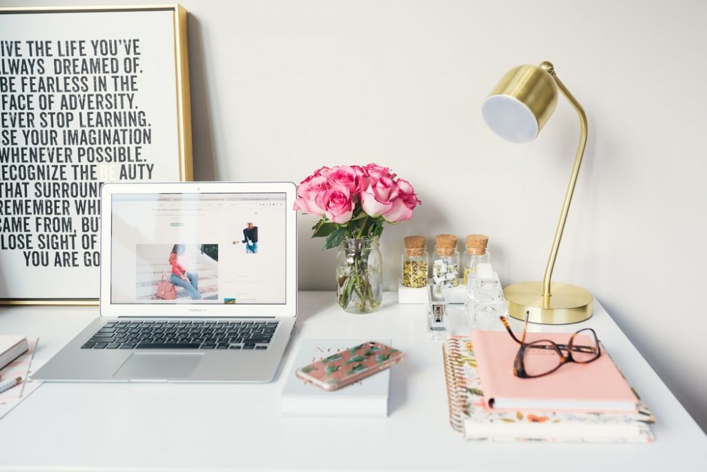 Mesa de trabalho com laptop, abajou, rosas em um vaso, potes organizadores com material de escritório - Marie kondo
