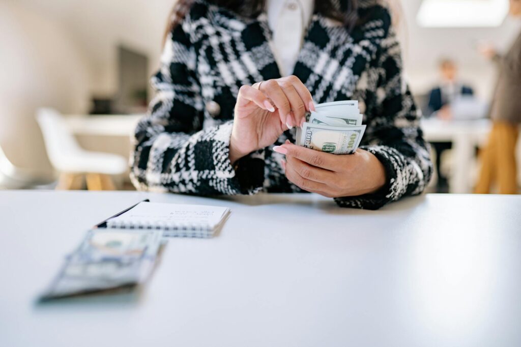 a person in black and white plaid jacket holding banknotes