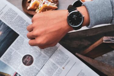 person wearing watch near the newspaper