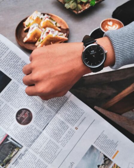 person wearing watch near the newspaper