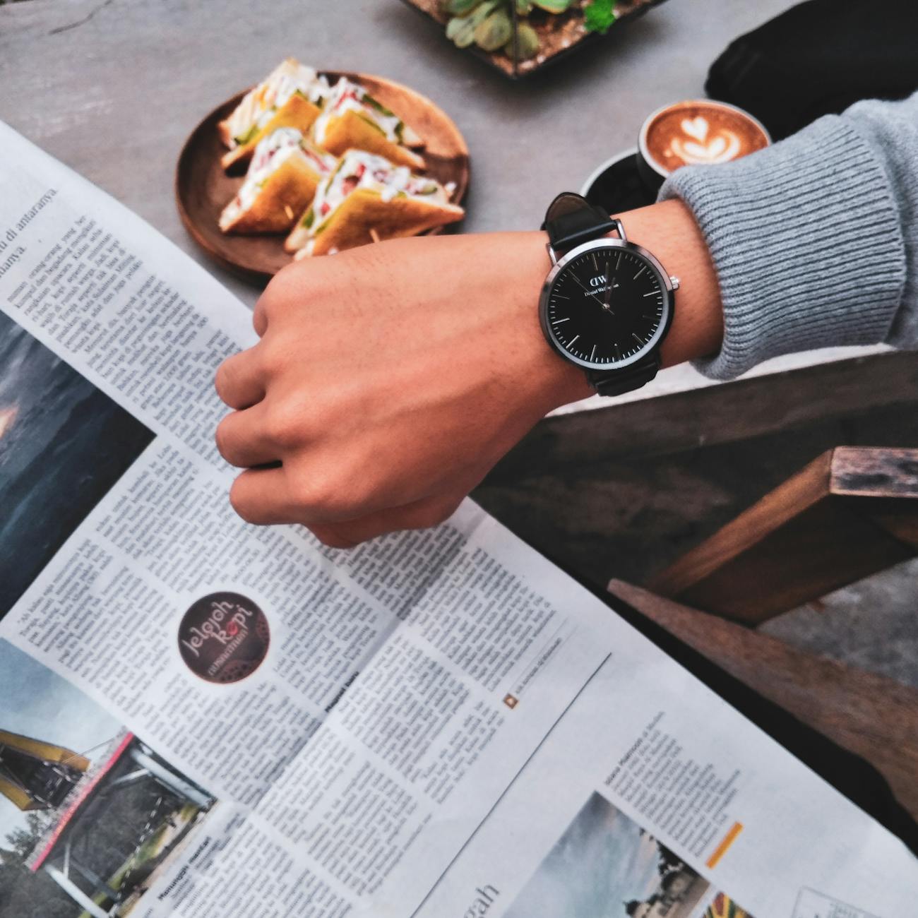 person wearing watch near the newspaper