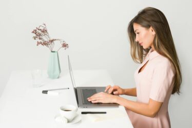 woman in pink dress using laptop computer