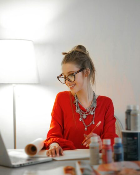 woman in red long sleeve shirt looking at her laptop