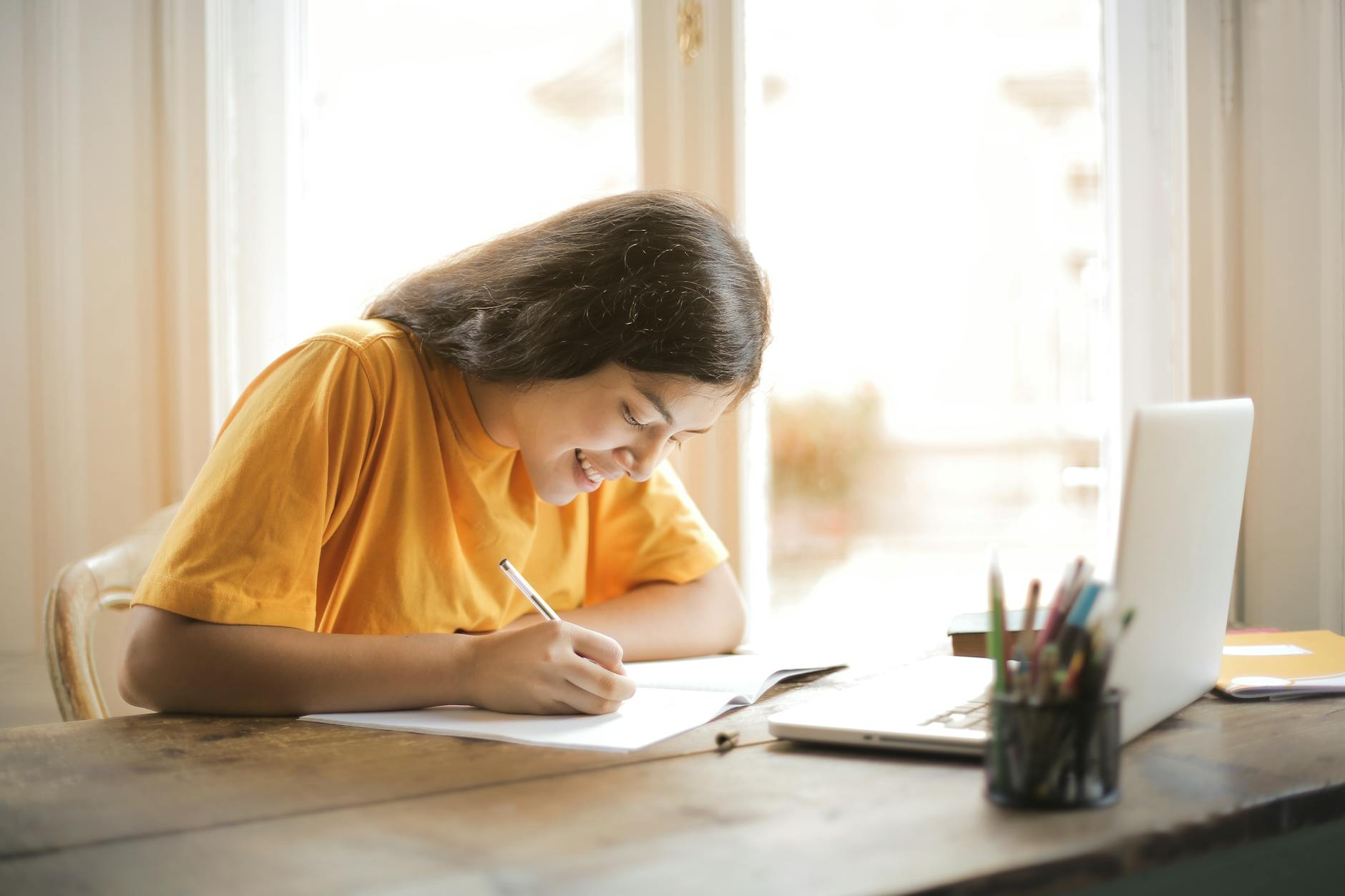 woman in yellow shirt writing on white paper