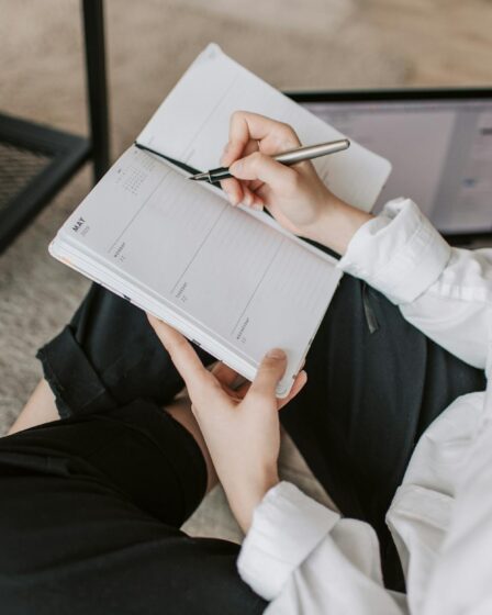 crop woman writing in notebook at home