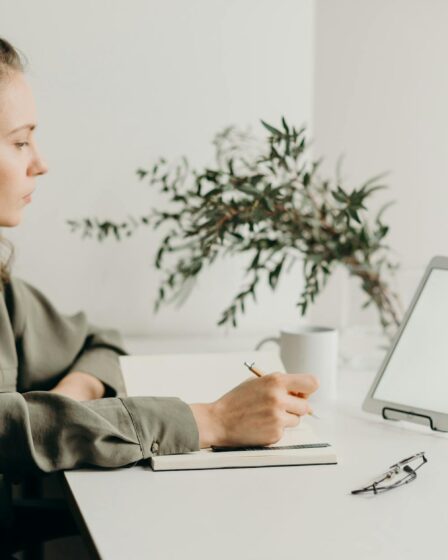 woman in gray coat using white laptop computer