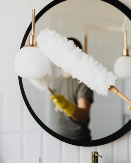 crop woman dusting lamp during housework