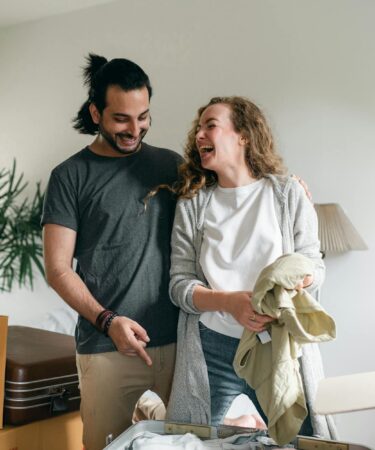 excited couple unpacking boxes in new apartment