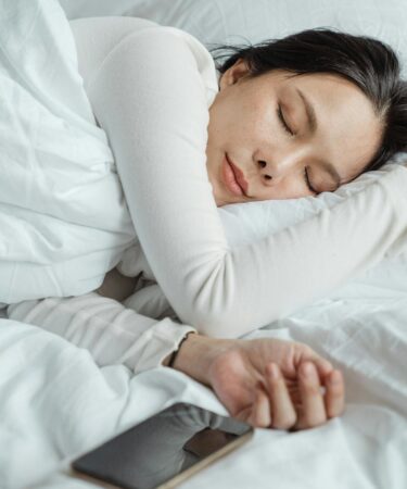 woman sleeping in bed near smartphone