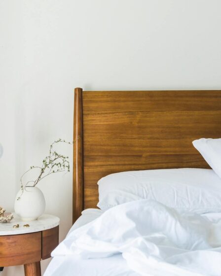 white bedspread beside nightstand with white and copper table lamp
