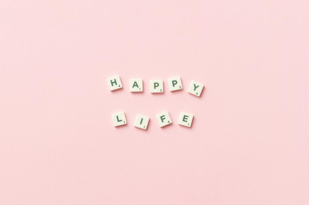 scrabble letters on a pink background spelling happy life