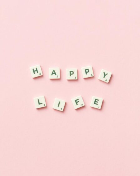 scrabble letters on a pink background spelling happy life