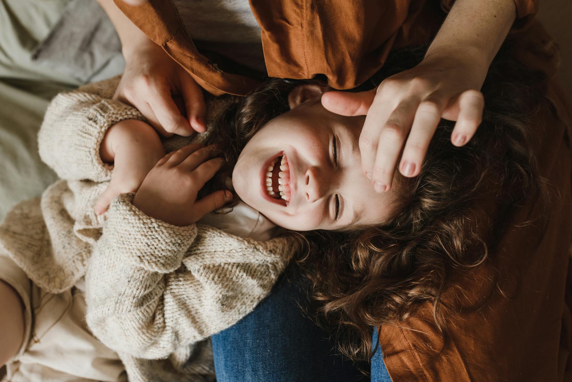 a child in a sweater lying on a person s lap